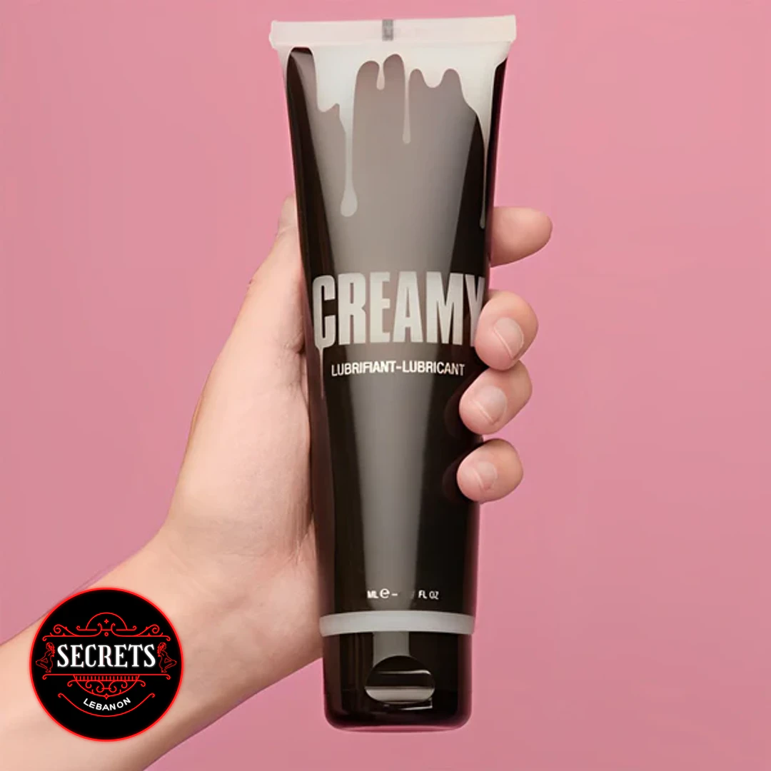 Creamy Cum Lubricant 150ml dark squeeze tube held against pink background