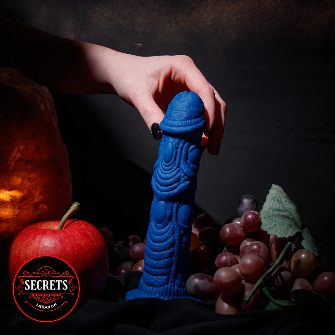 Draken Fantasy Silicone Dildo in blue held by hand over grapes