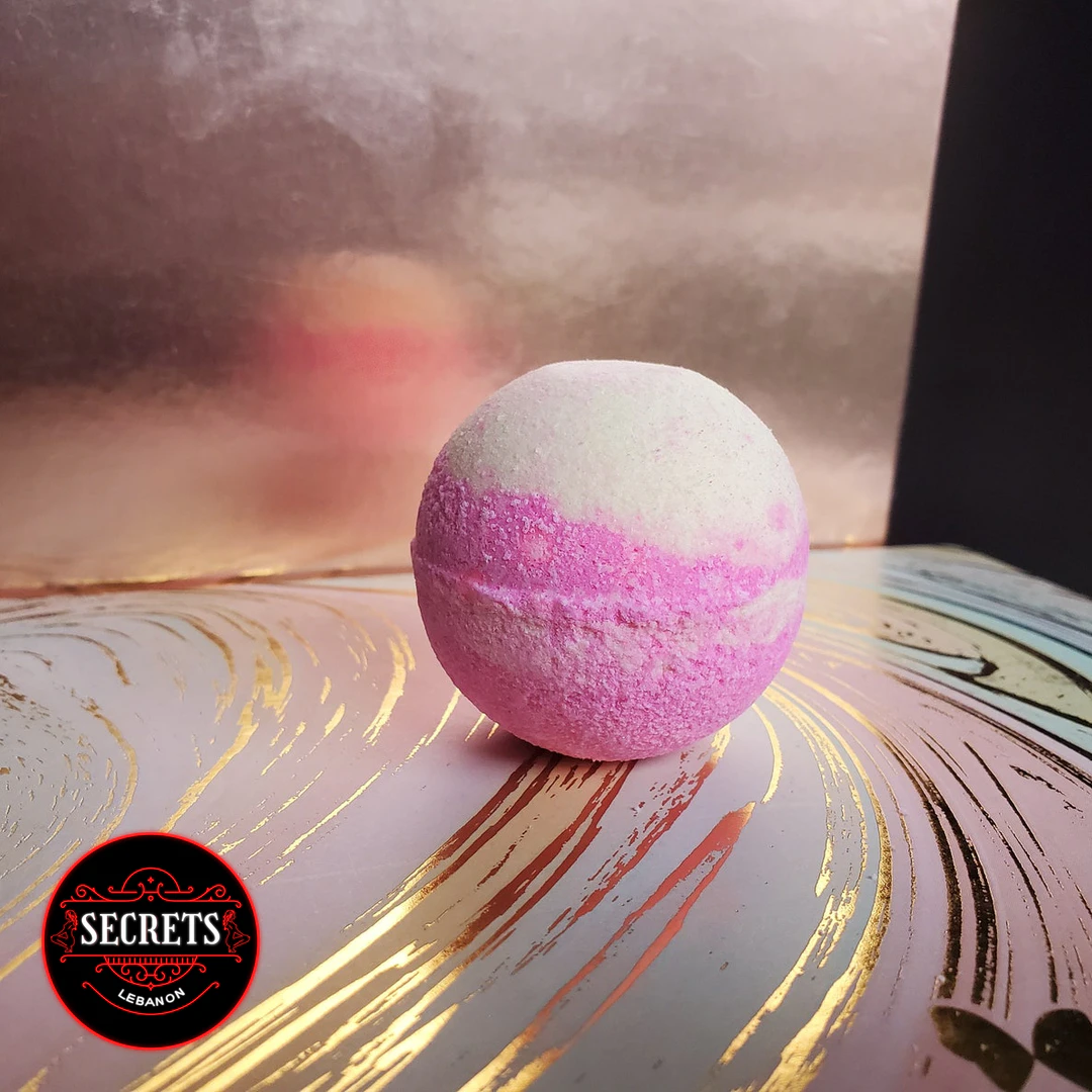 Pink Indulgence Bath Bomb with pink and white stripes on decorative surface