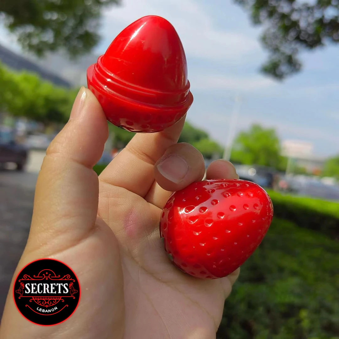 Strawberry Kiss Lip Balm open two-piece red strawberry-shaped container held outdoors