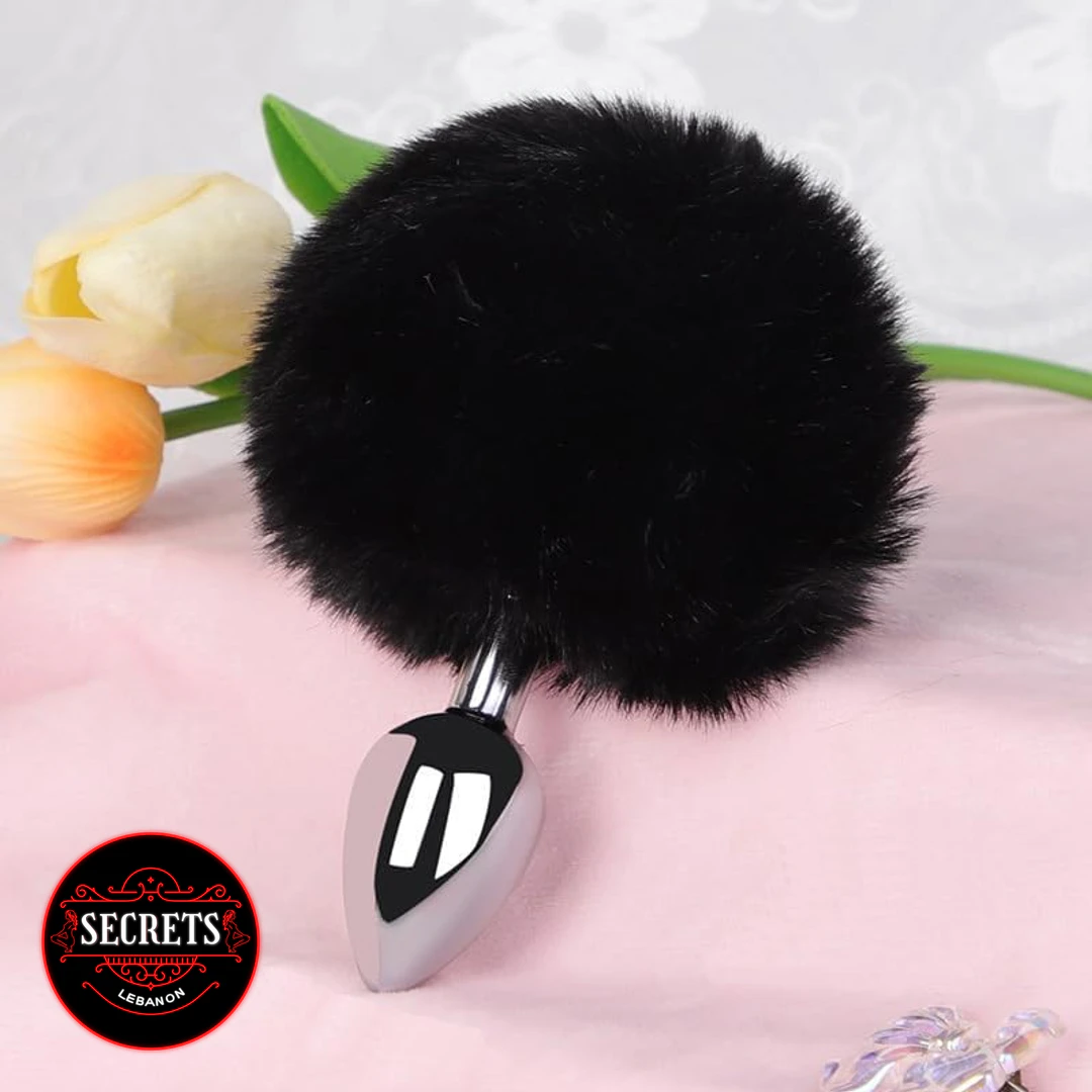 Darkness Pom Pom Steel Anal Plug with black fluffy pompom on pink surface